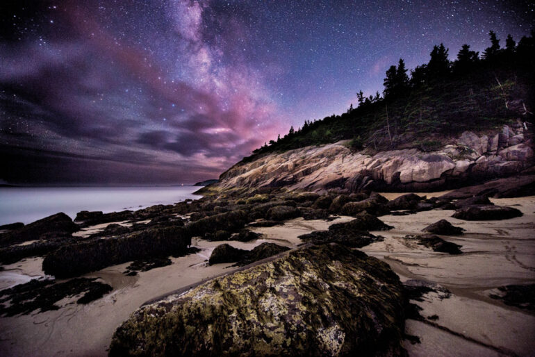 the starry night sky over Sand Beach in Acadia National Park