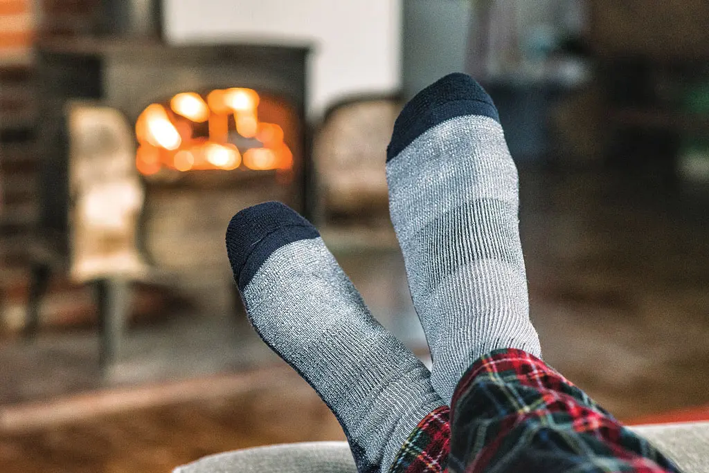 sock-covered feet propped up near a woodstove