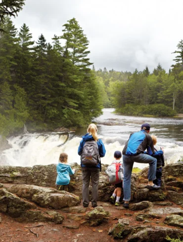 The author, Lewis Robinson (in ballcap), and his children, Maisie and Leo (without backpacks), soak up the spectacle of Grand Falls with their hiking companions.