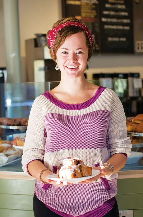 A woman smiling and holding a pastry at Lil’s