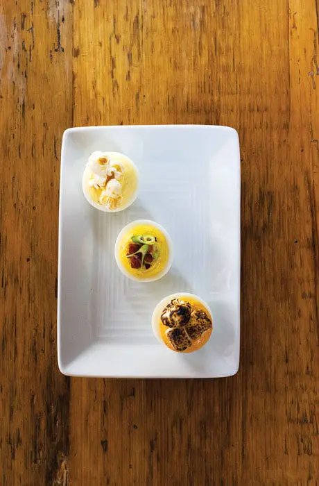 Deviled eggs with popcorn, chorizo, and toasted marshmallow plated on a white rectangular plate from the Black Birch