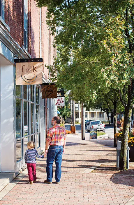 A father and son walking beneath the sign for artisan boutique Folk on the streets in Foreside.