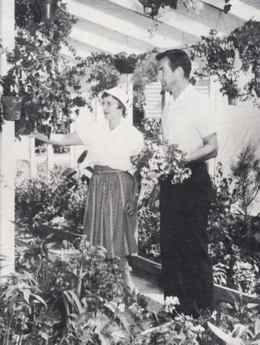 black and white photo of two people standing in a garden room