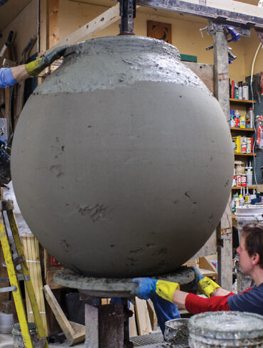 People working on large clay urn