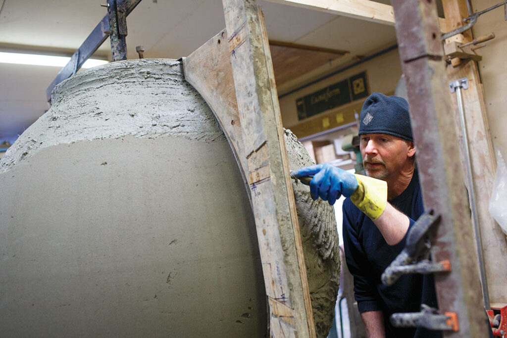 man working on large urn