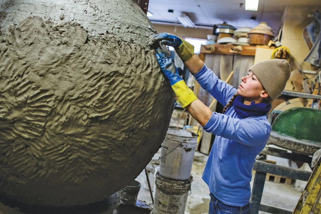 woman working on large clay urn