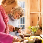 Women pouring drinks in kitchen