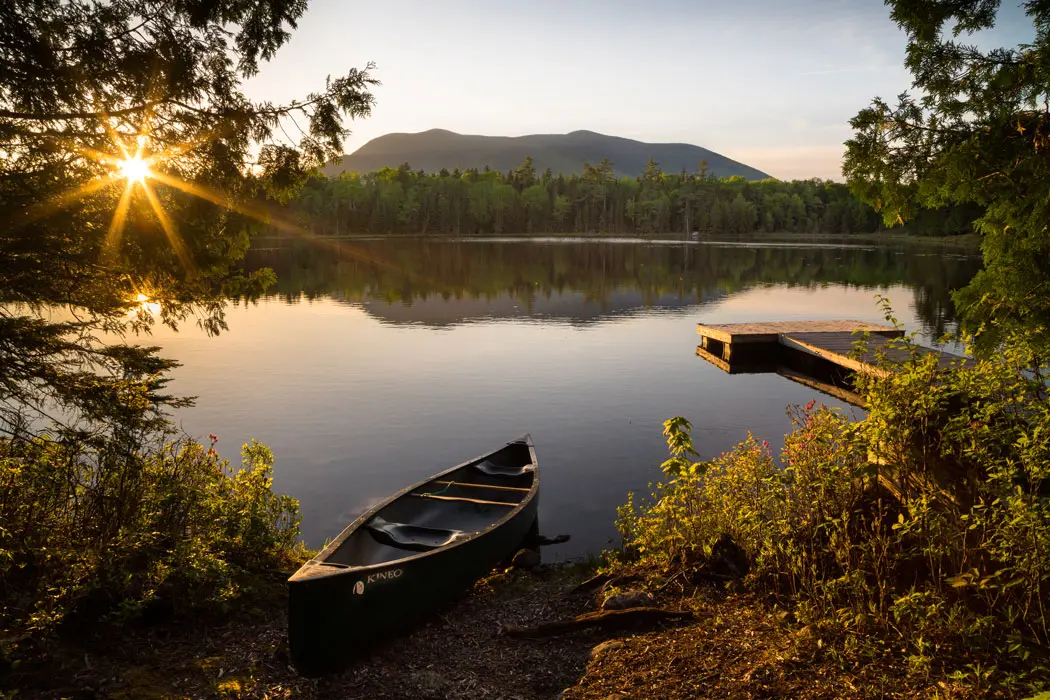 canoe on land next to lake and mountians