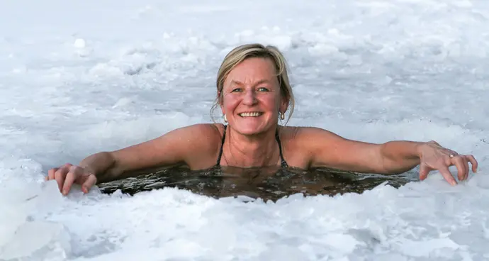 Outside the sauna, Erja Lipponen, of Camden, takes a dip through a hole in the ice.