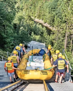 large group of people carrying raft down to water