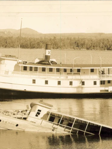 old photo of a steamboat next to another sinking steamboat on Moosehead Lake