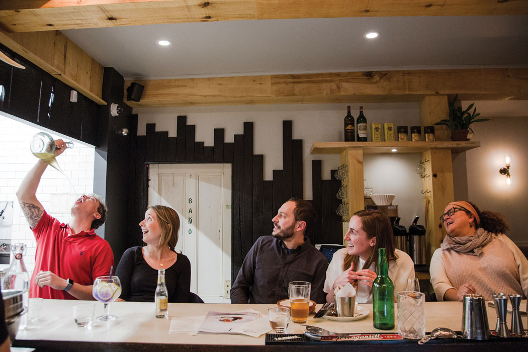 Bar guests partake in the Spanish tradition of drinking from a communal porron wine pitcher.