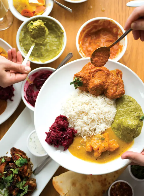 A shareable meal of lamb meatball curry, palak paneer, and butternut-squash and beetroot curries.