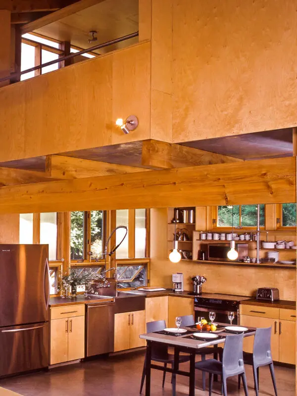 The kitchen walls and cabinets are Baltic birch. Gray Bellini chairs surround a Room & Board table with a maple top and steel legs.