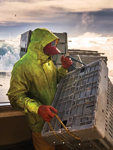 Dylan Smith, sternman aboard Sea Glass, loads a tote containing more than 100 pounds of lobsters into the fish hold. The fishermen navigate the boat’s open stern while motoring at up to 12 knots in high seas.