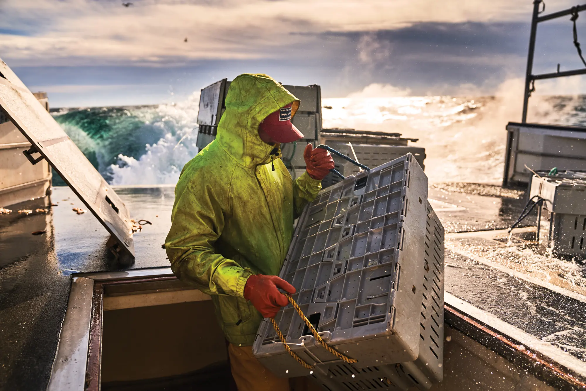 Dylan Smith, sternman aboard Sea Glass, loads a tote containing more than 100 pounds of lobsters into the fish hold. The fishermen navigate the boat’s open stern while motoring at up to 12 knots in high seas.