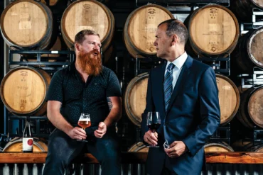 Beer aficionado Jack van Paepeghem (left) and wine pro Scott Tyree talk shop in Oxbow’s Portland barrel room.