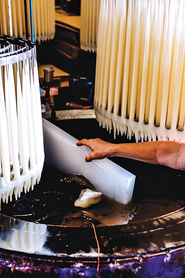 Danica Design employee adding wax to dipping machine