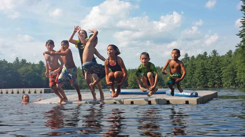 A group of kids jumping off a dock at Acres of Wildlife.	