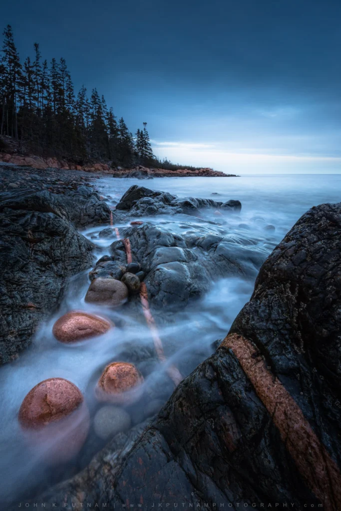 A magma intrusion and polished cobbles formed from the same granite on the coast of Acadia National Park, Mount Desert Island, Maine.