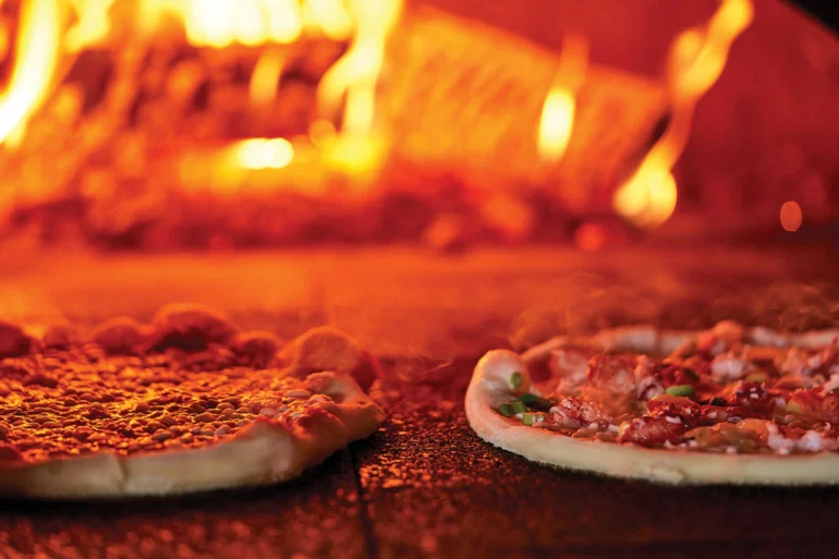 A lobster pizza cooking in a wood-fired oven
