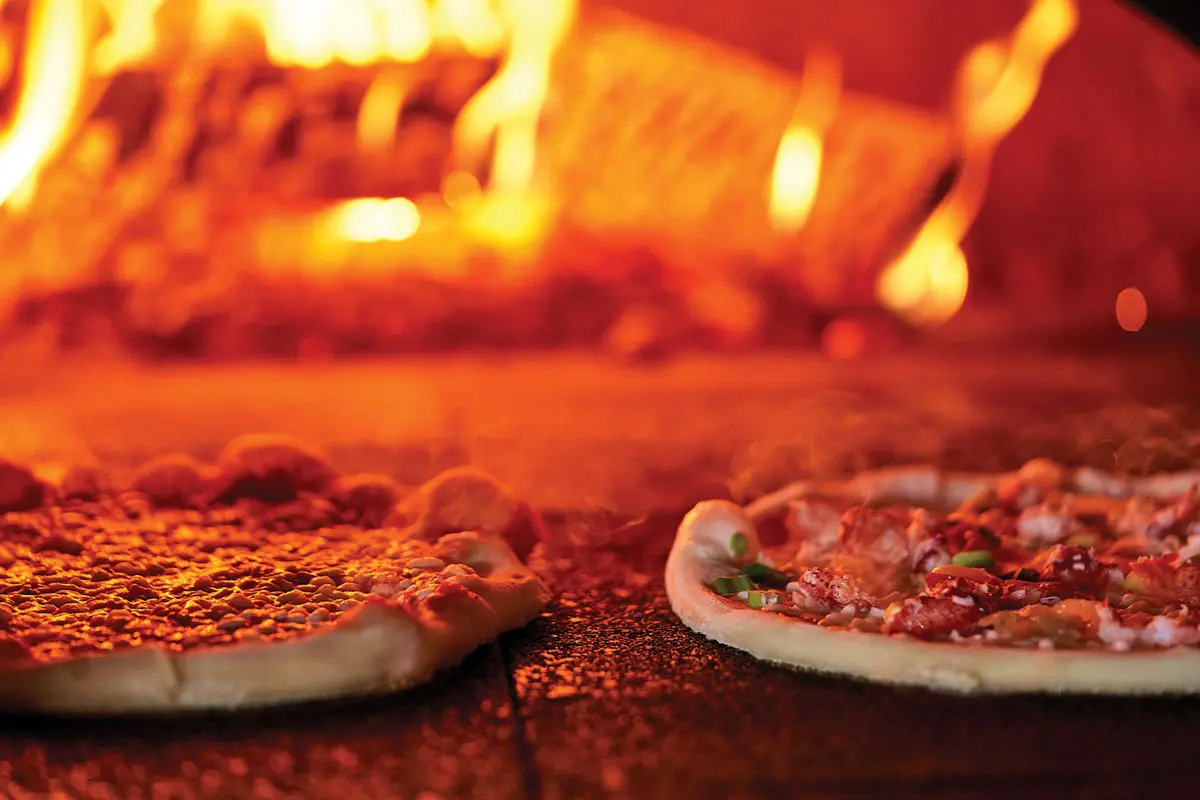 A lobster pizza cooking in a wood-fired oven