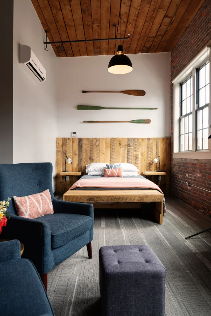Mill Inn bedroom. The bed's headboard and bench uses reclaimed wood. The room contains navy blue plush furniture.