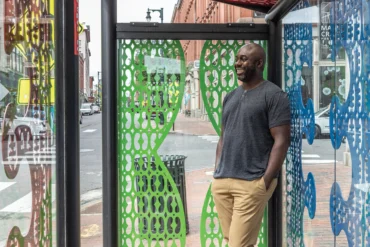 Ebenezer Akakpo standing in his contest-winning bus stop in Portland, Maine