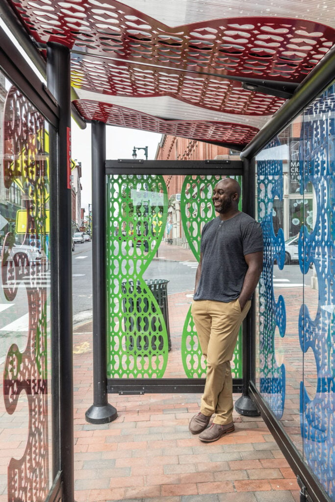 Ebenezer Akakpo standing in his contest-winning bus stop in Portland, Maine