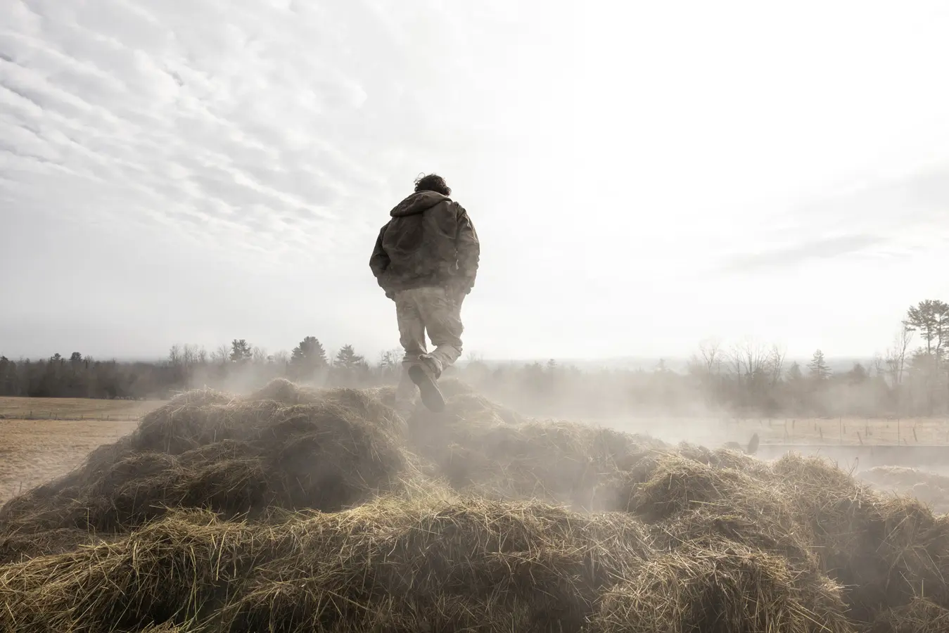 Alister Holmes, of Misty Brook Farm, walks through a pile of manure mixed with straw bedding.