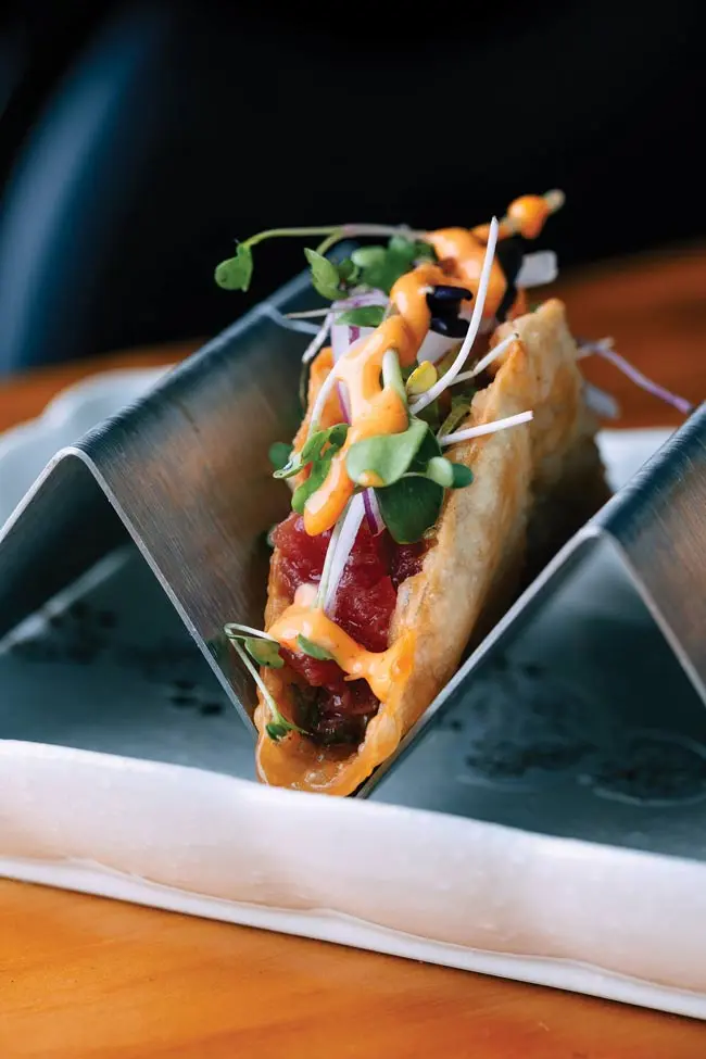 A sushi taco with tuna, microgreens, red onion, and spicy mayo
