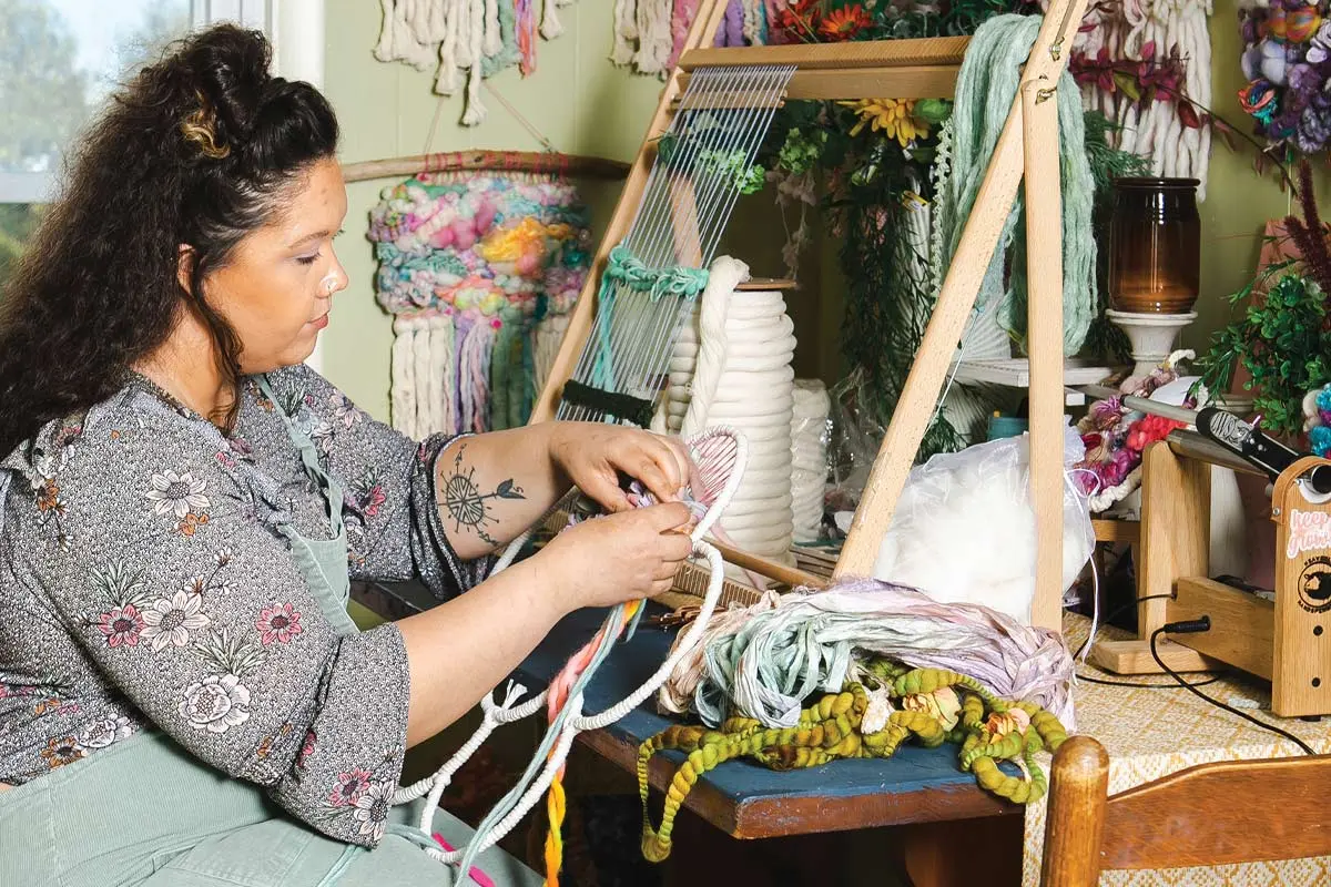 Halley Phillips, the artist behind WeavingsbyHalley, at the loom