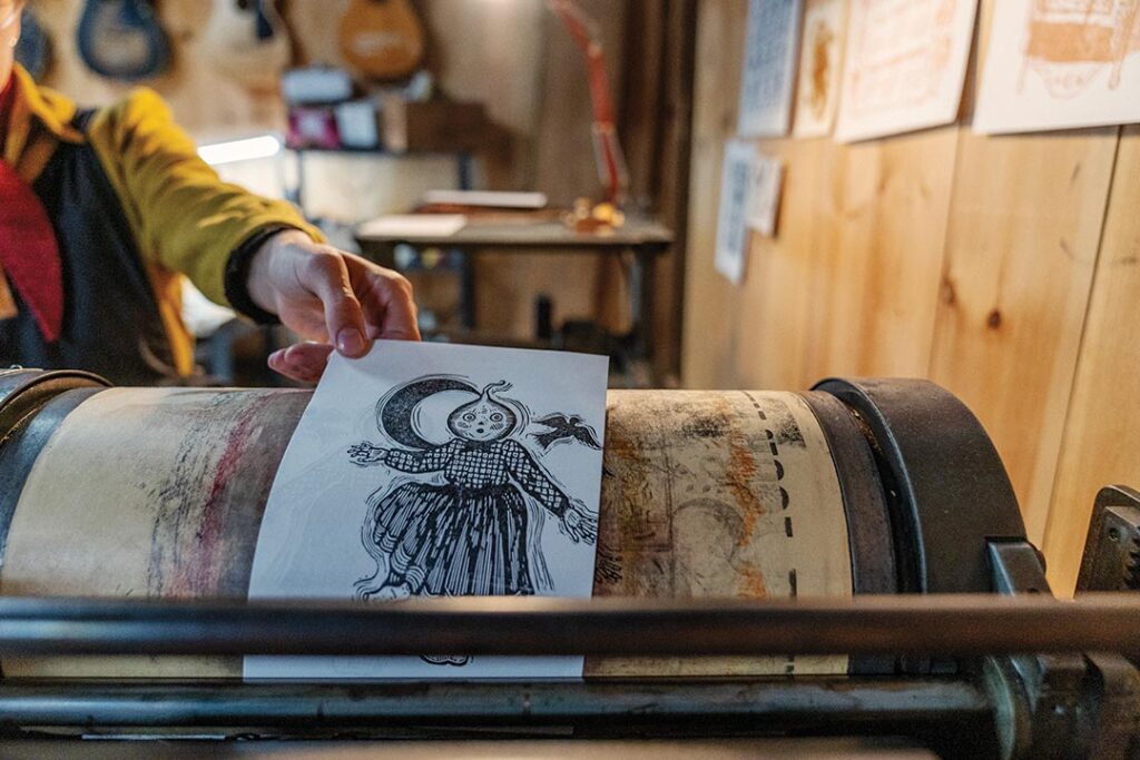 Addie Best pulling a print off of her Vandercook press