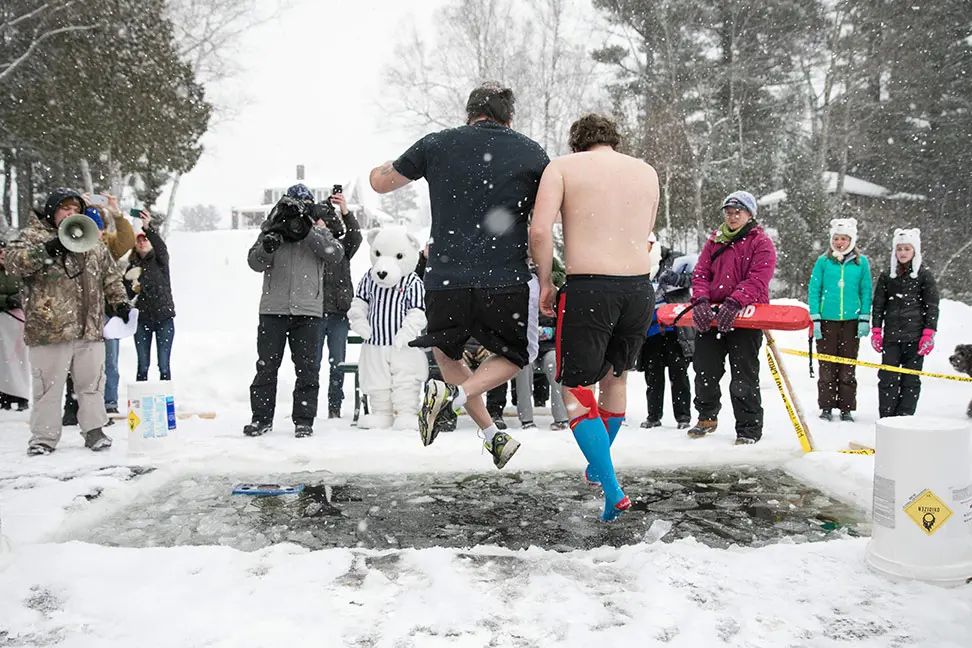 two men jumping into hole in ice