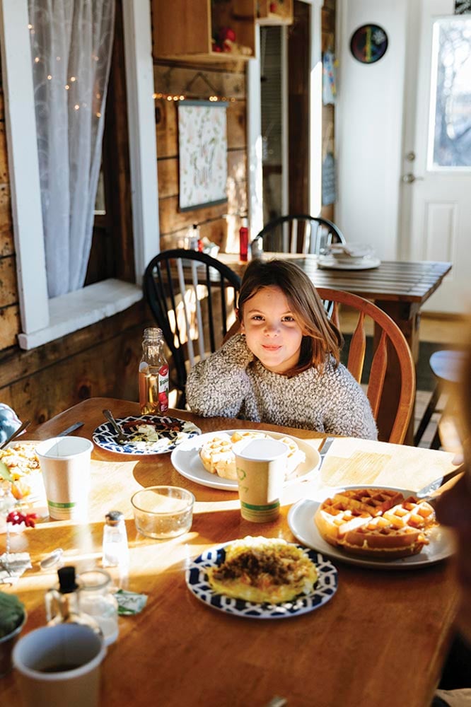 a child seated at the head of a table filled with waffles