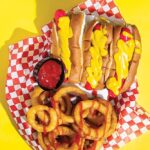 red hot dogs slathered i mustard, with onion rings drizzled with ketchup
