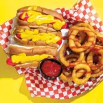 red hot dogs slathered i mustard, with onion rings drizzled with ketchup