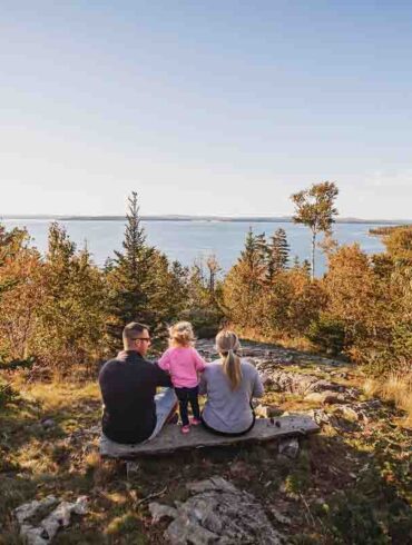 family sitting on a bench in one of Maine Coast Heritage Trust's preserves