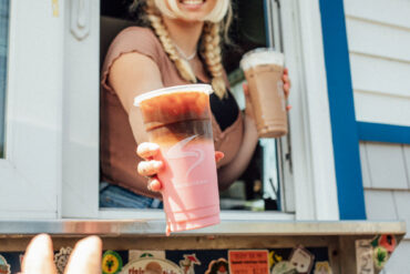 aroma joe's barista handing drinks out of the drive-through window