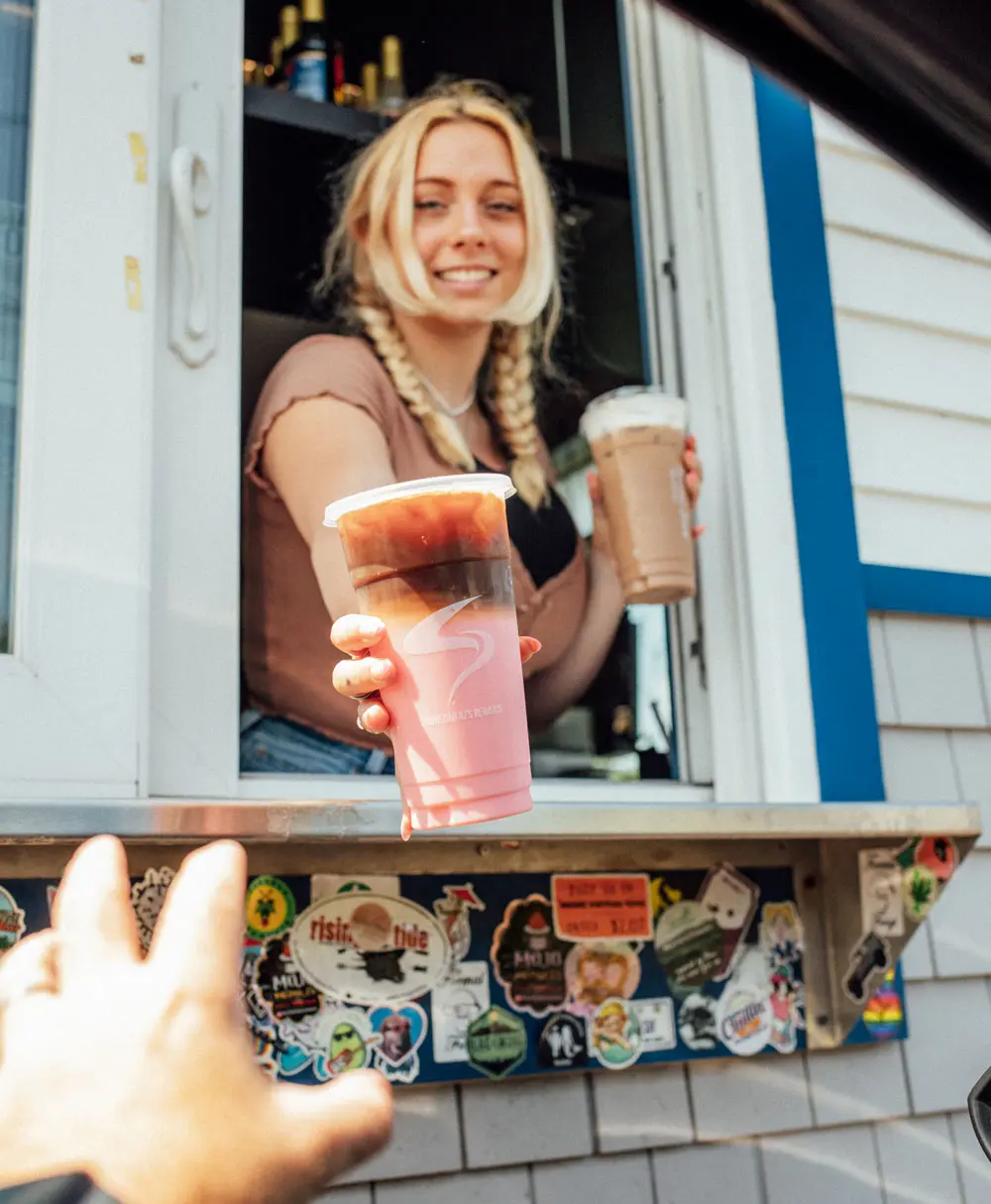 aroma joe's barista handing drinks out of the drive-through window