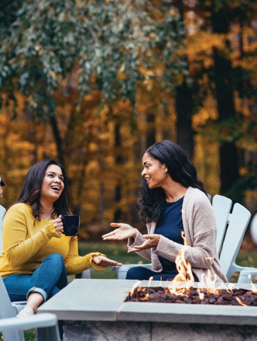 three people socializing around a propane-fueled fire pit