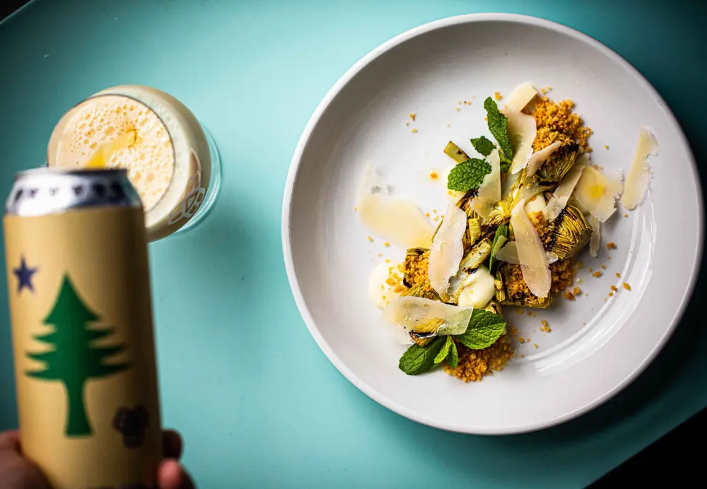 Bissell Brothers beer being poured into a glass next to an elegant plate of food
