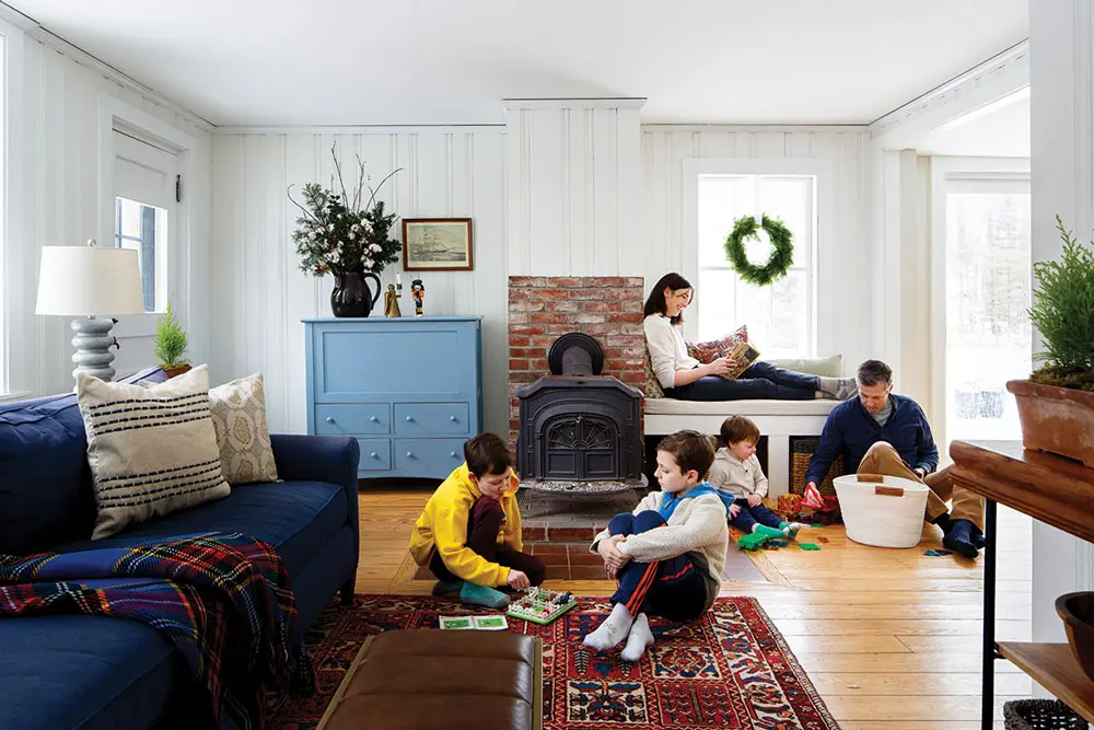 in the keeping room, a blanket chest, painted in Benjamin Moore’s Nova Scotia Blue, conceals firewood and pops against beadboard walls in the company’s Harwood Putty