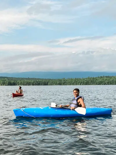 Two teens kayaking on a lake in maine