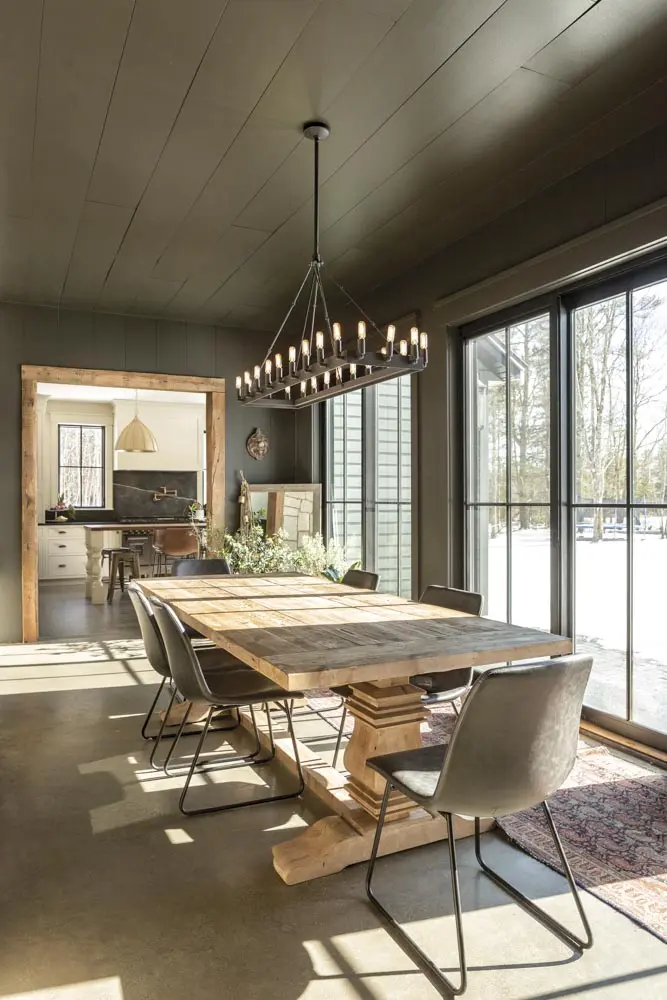 in the dining room, an RH forged-iron chandelier and an antique oak table with kid-friendly faux-leather Target chairs and an antique runner from Freeport’s Pillars