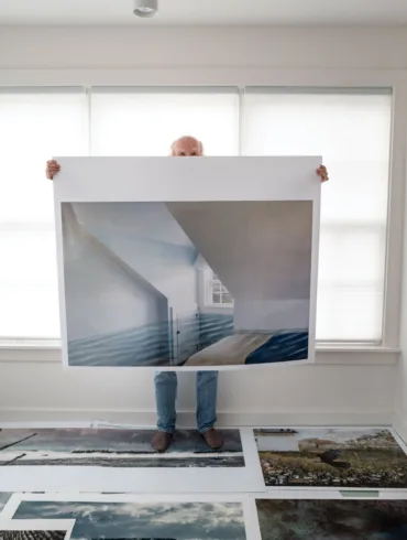 Jeffery Becton holding up a print of "Olivia's Room," one of his photomontages