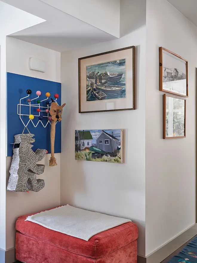 A sculpture by South Portland’s Karen Gelardi and a mask by Colin Sullivan-Stevens dangle from an Eames coatrack mounted on a leftover kitchen-cabinet panel in the entry