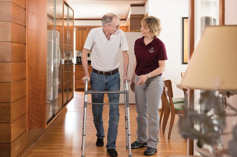 Androscoggin Home Healthcare and Hospice employee assisting man with walker