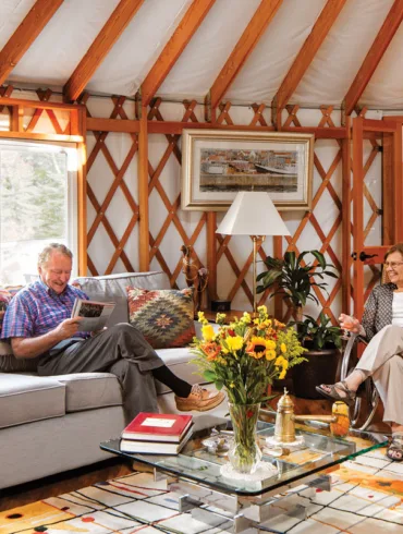 Tom and Sharon Minogue sitting the in living room area of their two-story linked Maine yurt