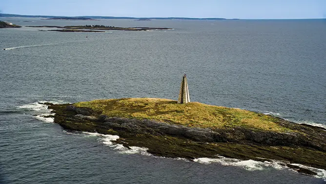 Aerial stock photo of a view of a lighthouse on Little Mark Island in the Atlantic Ocean; Harpswell, Maine